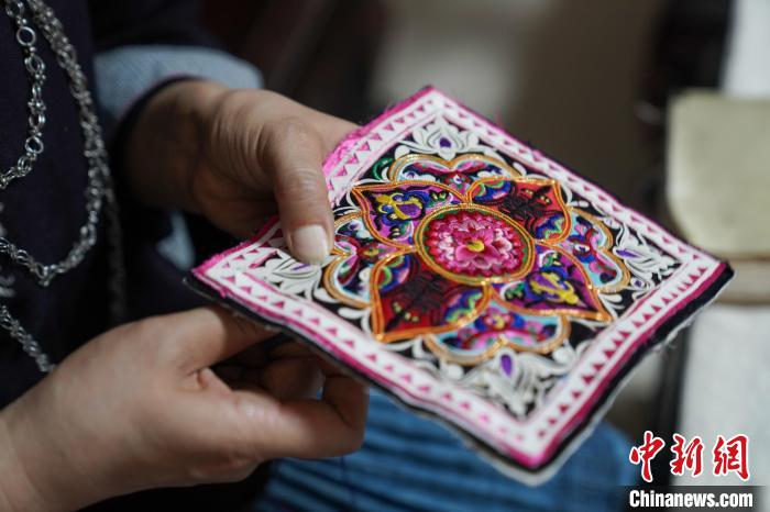 黄碧瑜正在背带上穿针引线。　王以照 摄