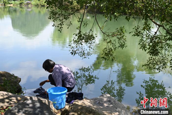旧州景区内，一位妇女在河边洗衣。　王以照 摄