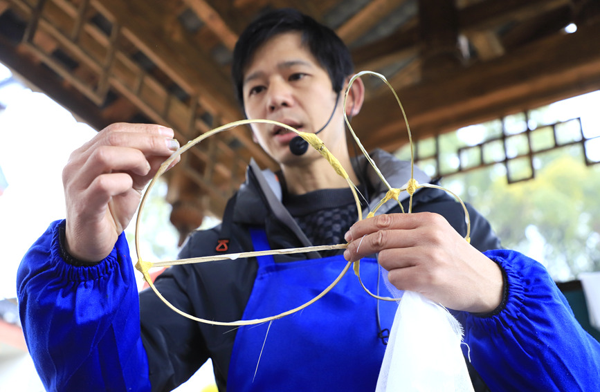 桂林市非物质文化遗产“两江龙灯”传承人梁家庆正在教小朋友制作龙灯。阳海翔摄
