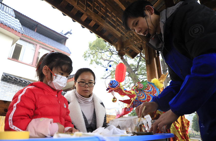 桂林市非物质文化遗产“两江龙灯”传承人梁家庆正在教小朋友制作兔子灯。阳海翔摄