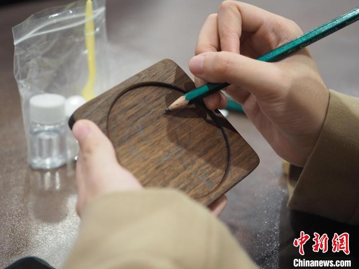 图为一名留学生在杯垫上绘制图案。　李娇阳 摄