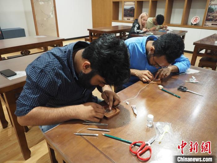 图为留学生们在制作苗族银饰掐丝画杯垫。　李娇阳 摄