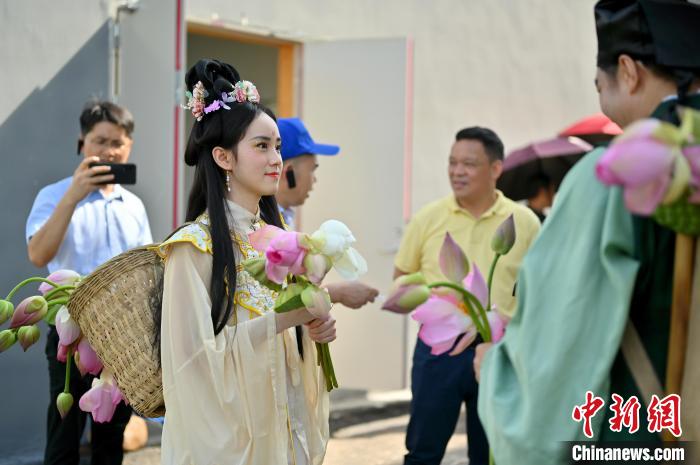 图为身着古装的表演者手持荷花巡游。　俞靖 摄