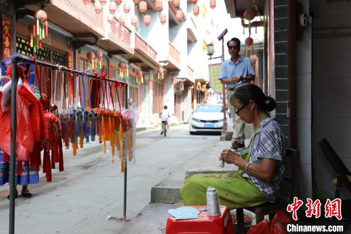 图为巷子里的民众正制作手工绣球。文嘉仁 摄