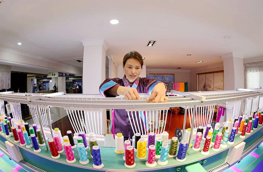 图为绣娘正在生产绣片。