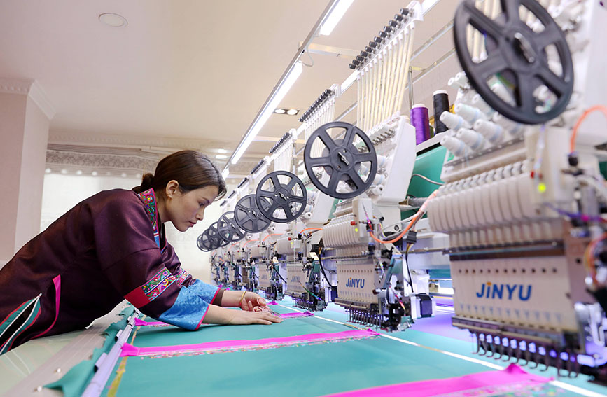 图为绣娘正在生产绣片。